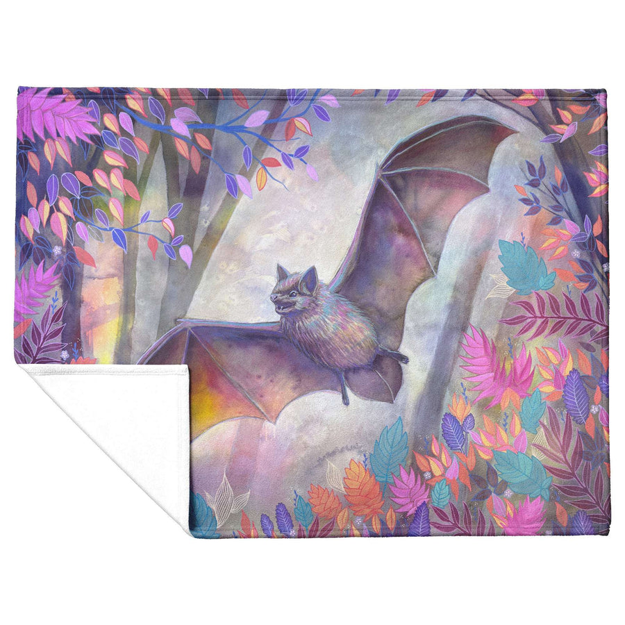 Bat Blanket with a folded corner to show the fleece underside, with a colorful artistic illustration of a bat with spread wings amidst vibrant, multicolored foliage.