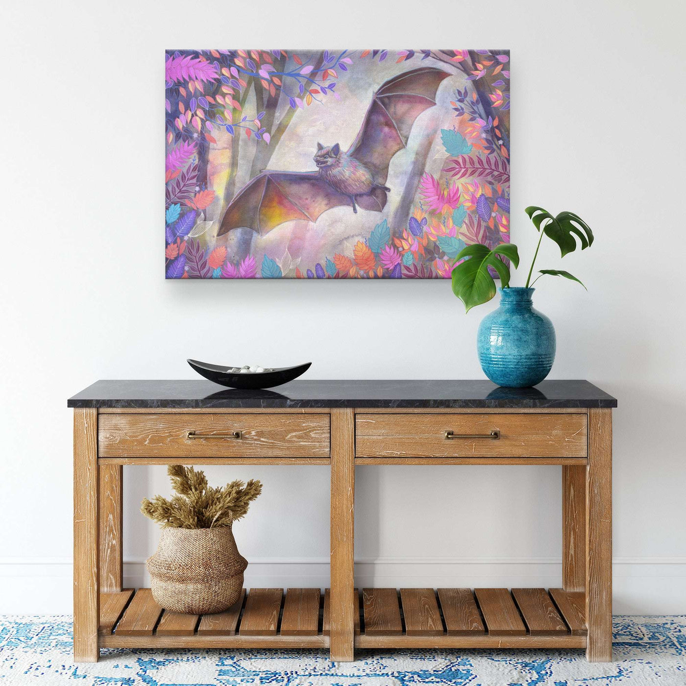 A decorated wooden console table against a white wall with a Canvas Bat Print above it