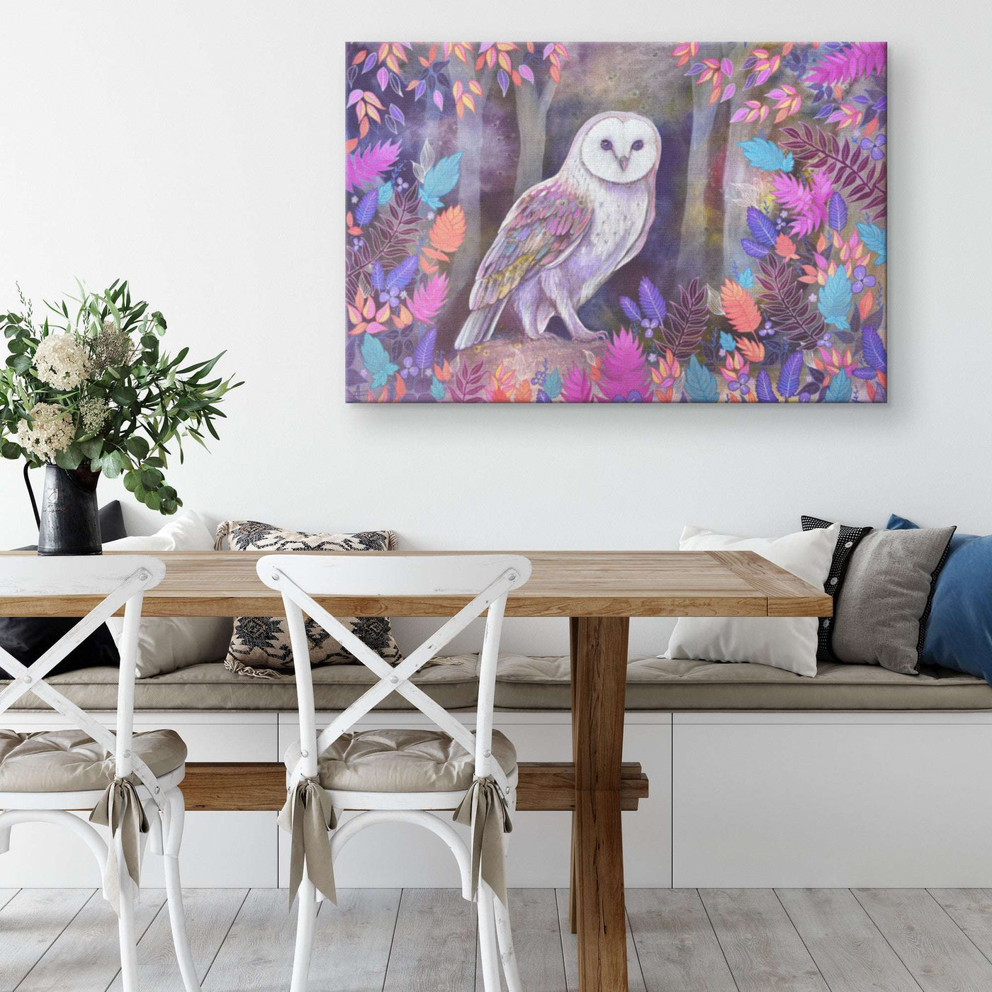 A vibrant Canvas Owl Art Print of a white barn owl perched amidst colorful foliage hangs above a modern wooden dining table.