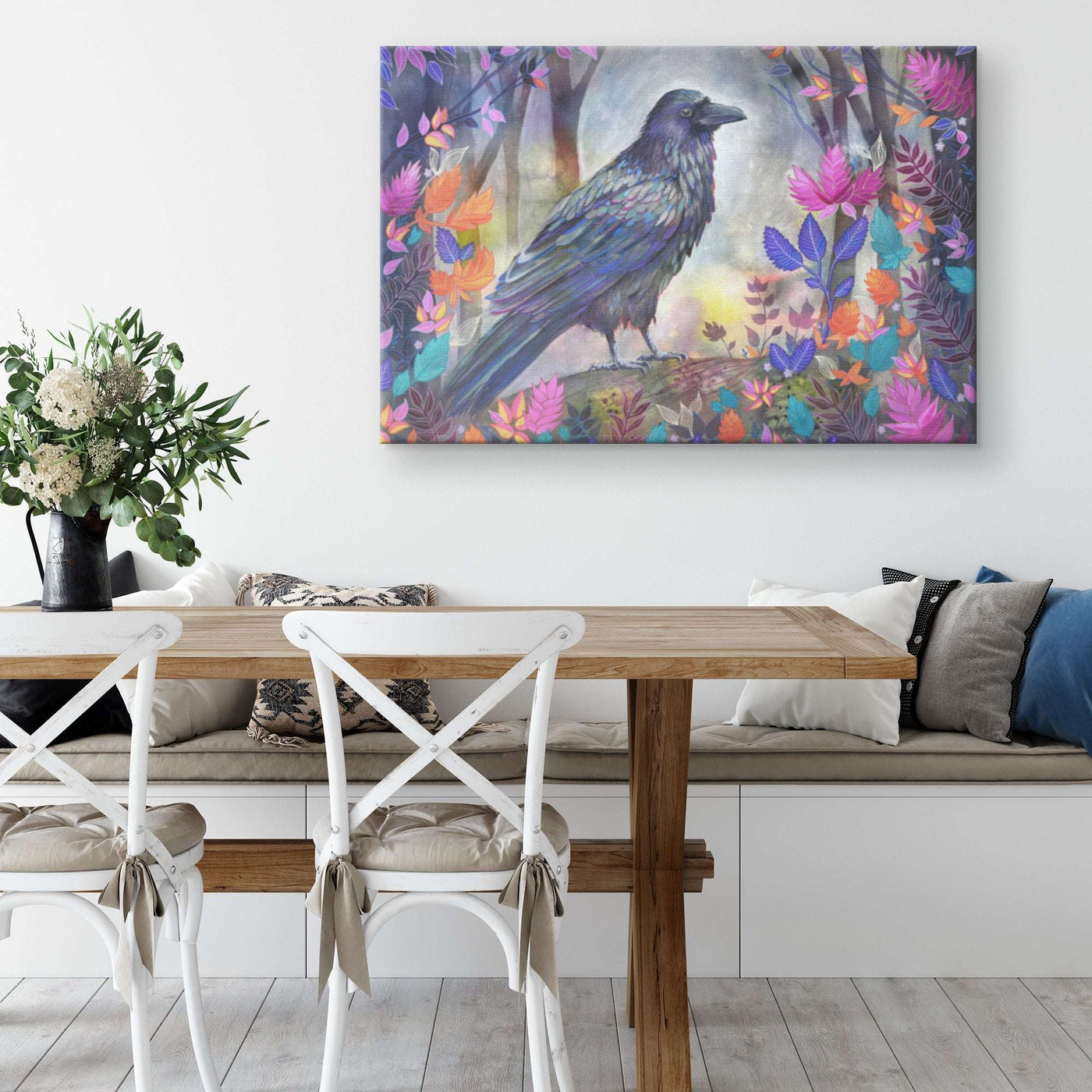 A vibrant Canvas Raven Art Print of a crow among colorful flowers hanging above a wooden dining table.