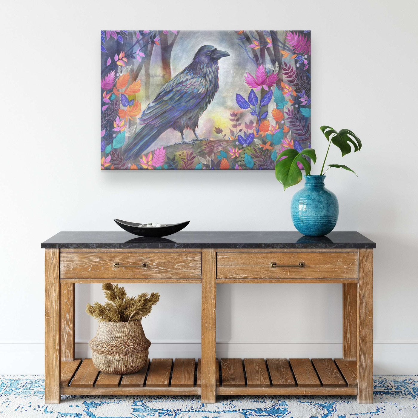 A colorful Canvas Raven Art Print of a raven among vibrant flowers hangs above a wooden table.