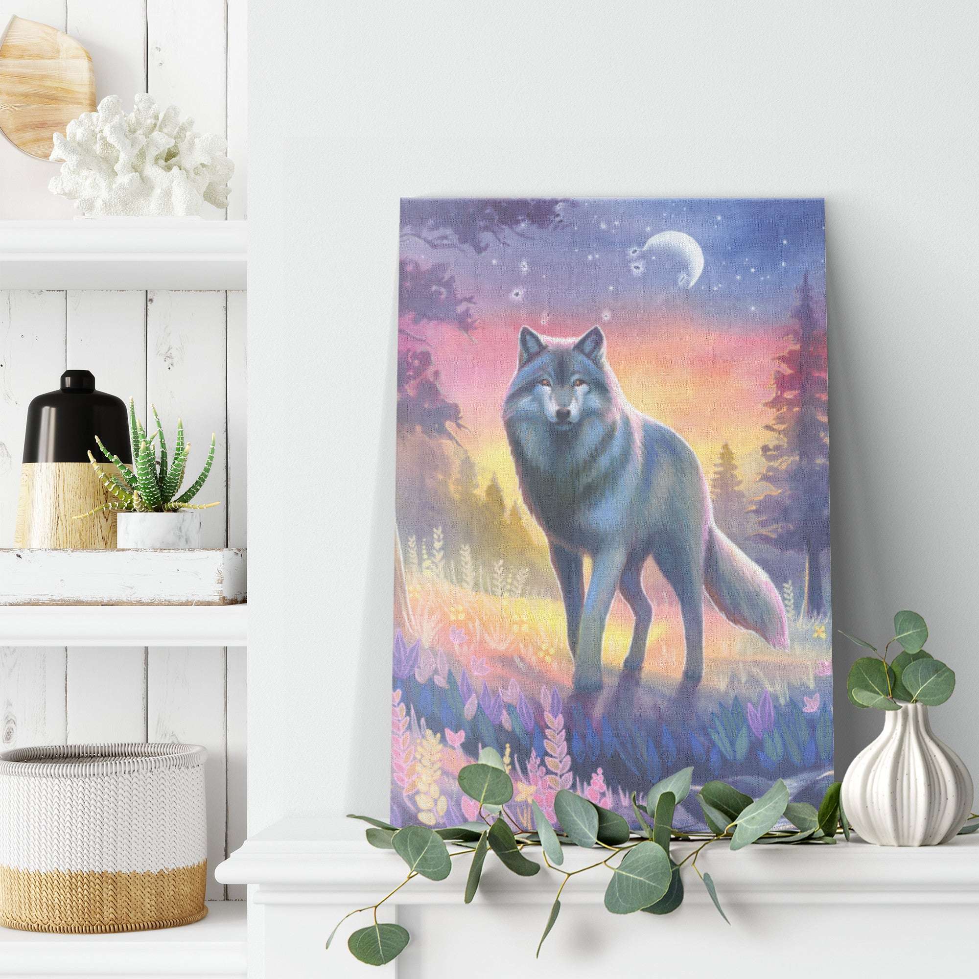 A Canvas Wolf Print of a wolf standing in a forest at twilight, with a colorful sky and the moon above, displayed on a white shelf in a cozy room decor.