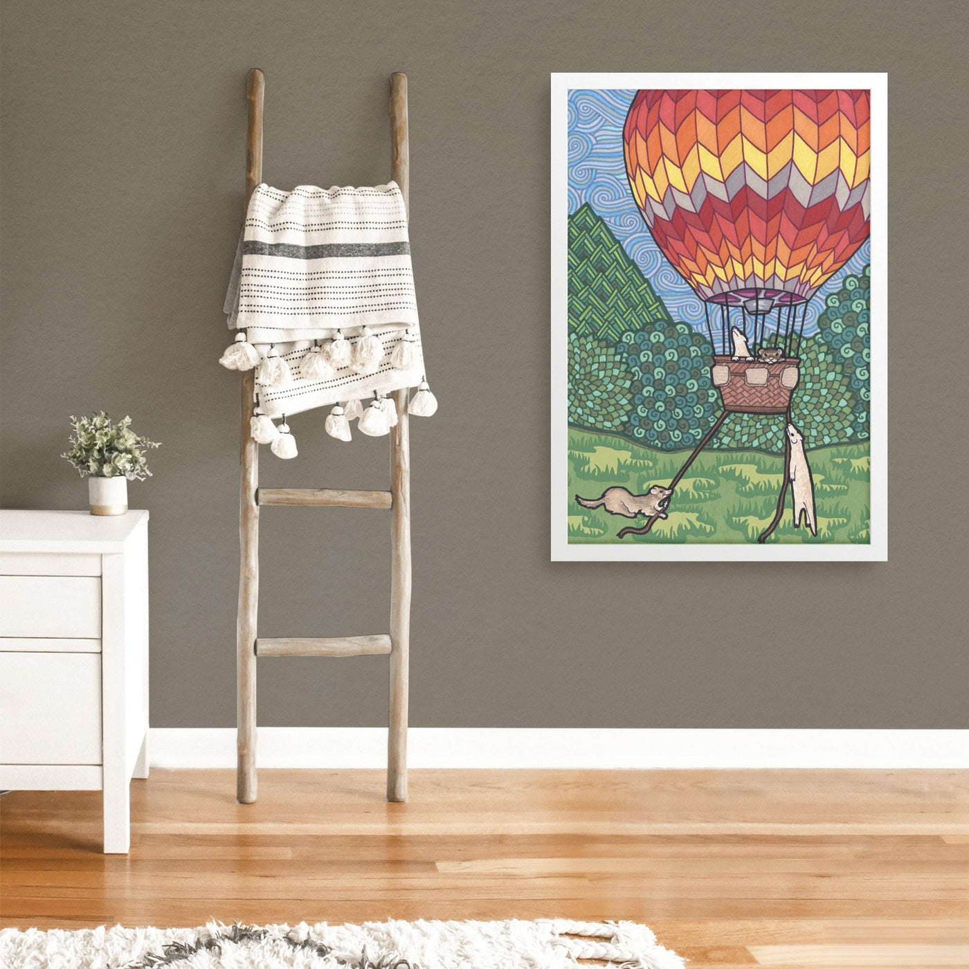 Colorful wall art depicting a hot air balloon and ferrets in a modern living room, featuring a Ferret Flight Framed Print.