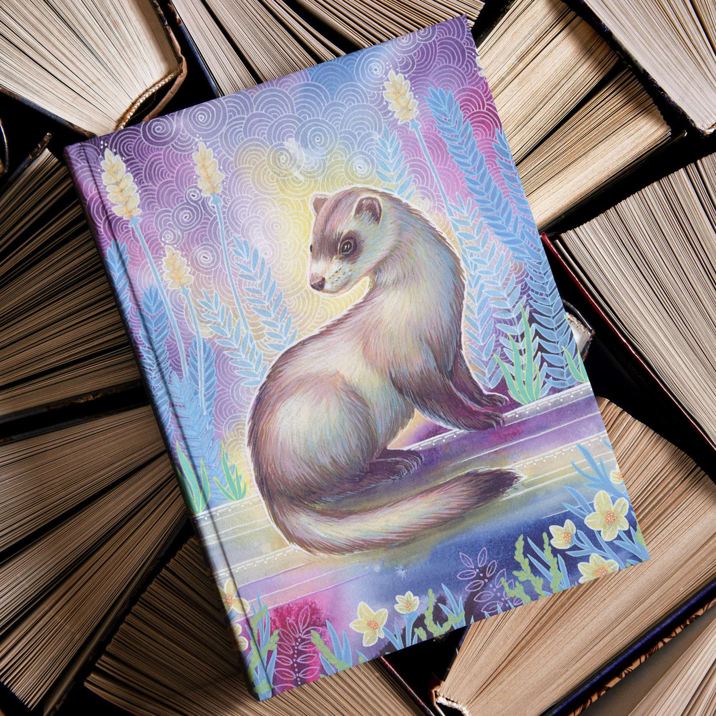 A Ferret Journal with a painted weasel on the cover, resting atop a stack of old, hardcover books.