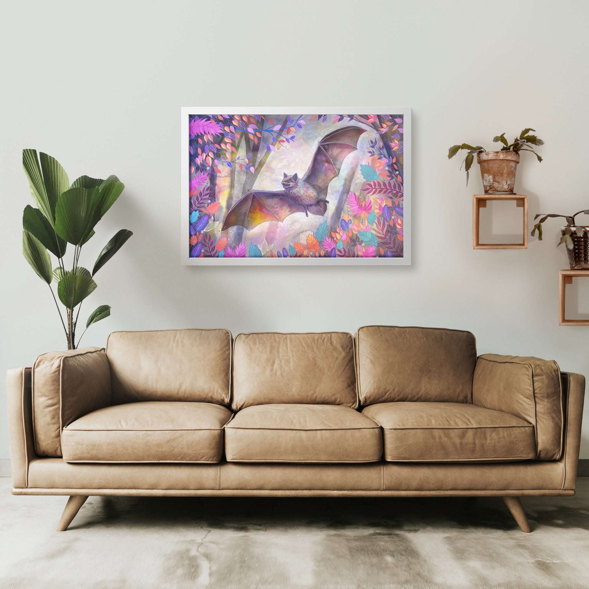 A modern living room with a large beige sofa centered under a Framed Bat Print of a colorful bat painting.