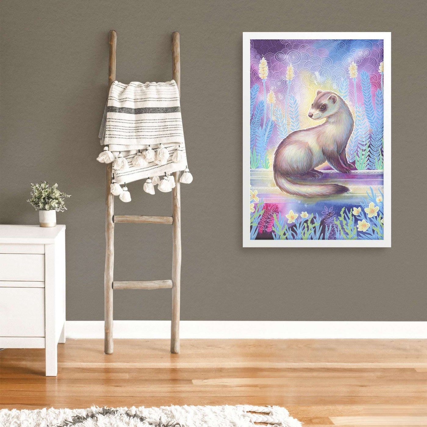 A Framed Ferret Print hung on a gray wall featuring a colorful ferret painting with flowers and intricate patterns.