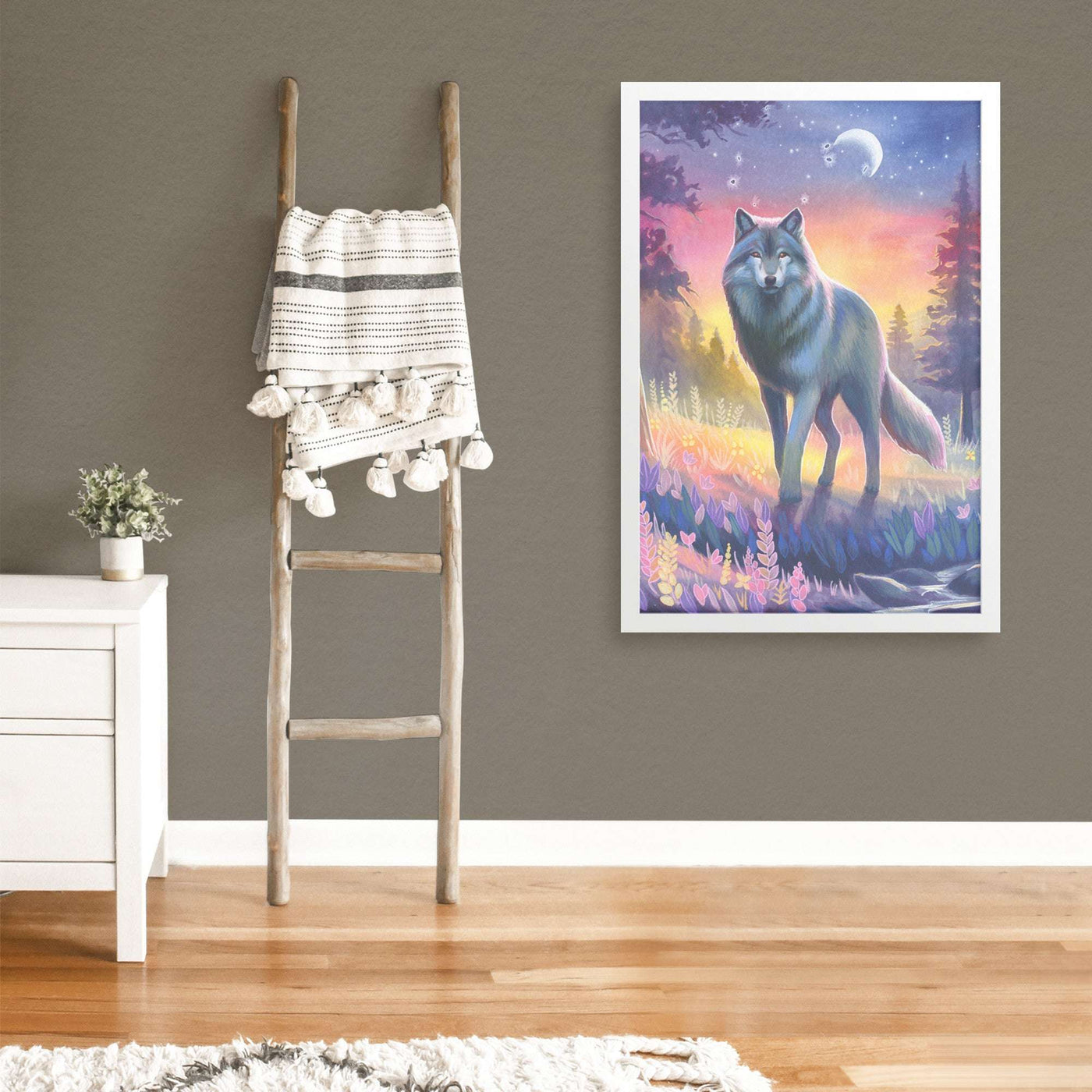 A vibrant Framed Wolf Art Print, displayed in a modern room next to a wooden ladder with hanging linens and a small white cabinet with a plant.