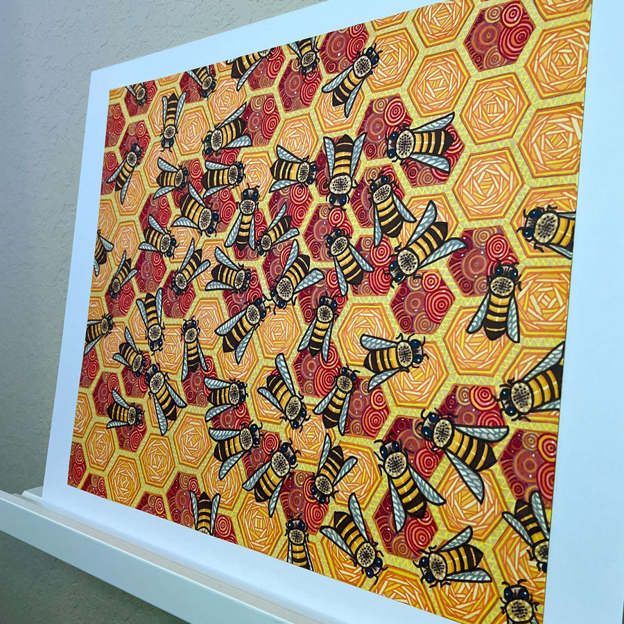 Angled view of a bee and honeycomb patterned artwork with a white mat.