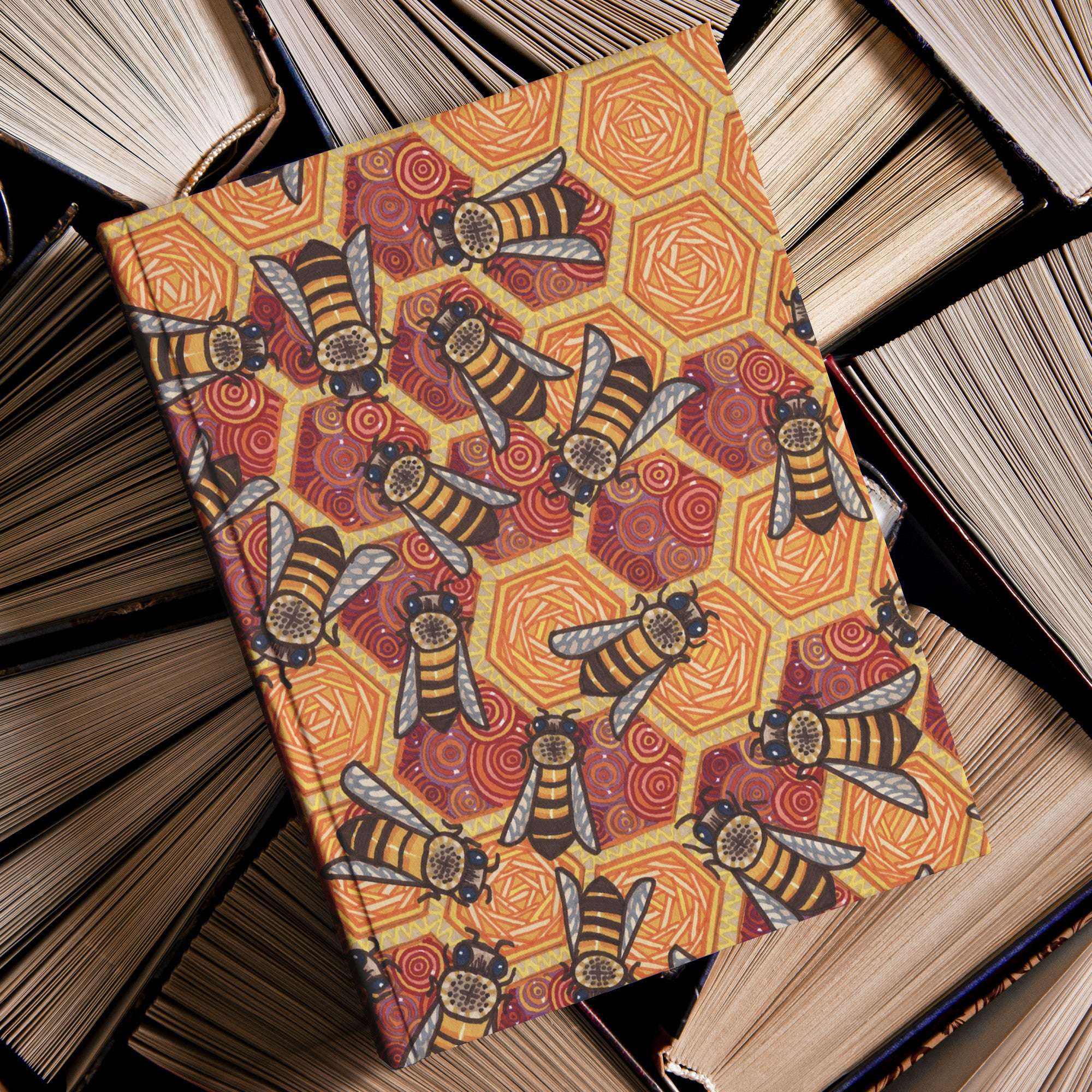 Journal with honeycomb and bee design on cover, resting on a pile of aged books.