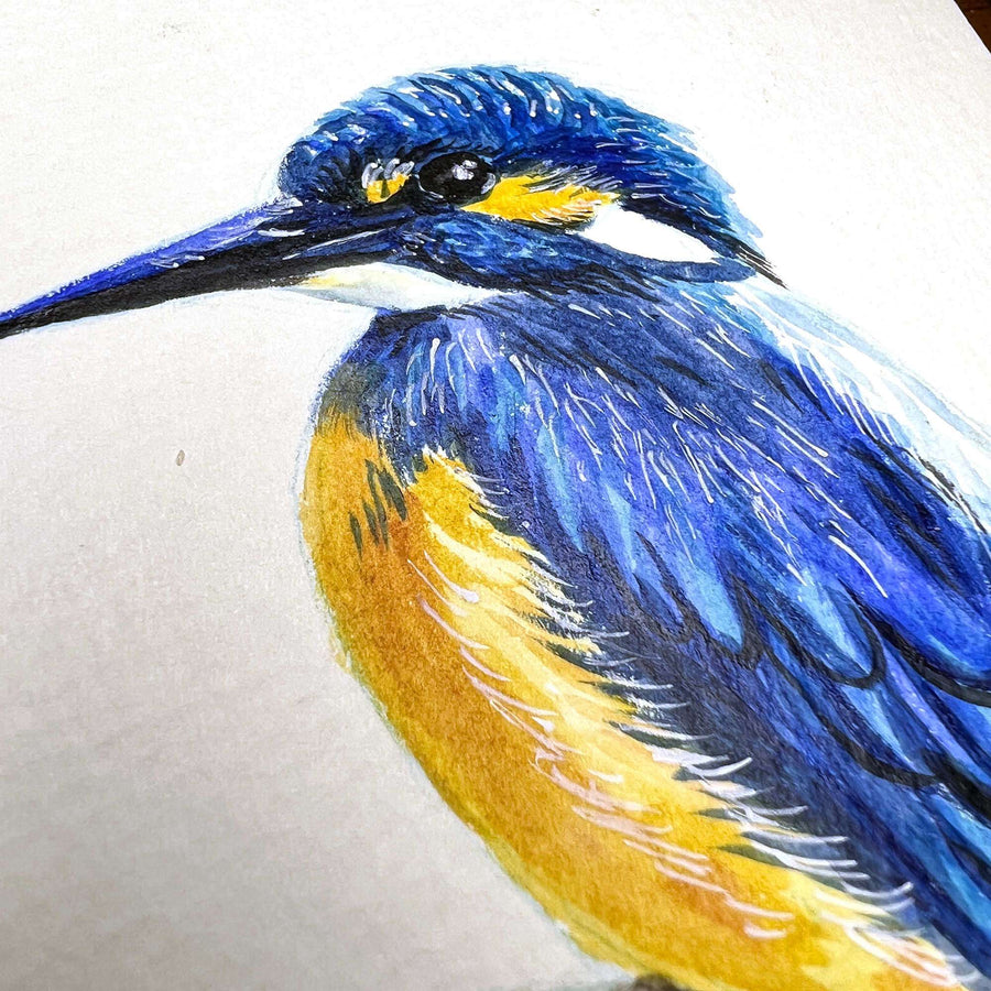 Close-up of a watercolor blue kingfisher on paper.