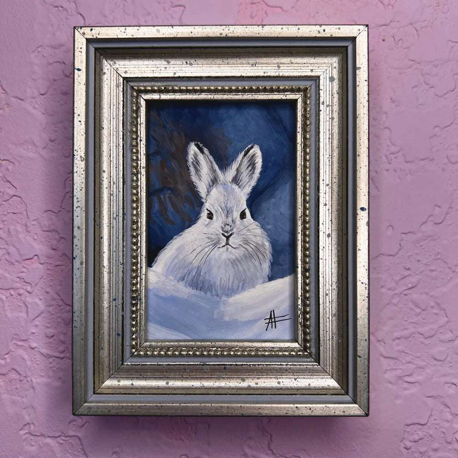 Snow rabbit mini portrait in vintage silver frame on purple wall.