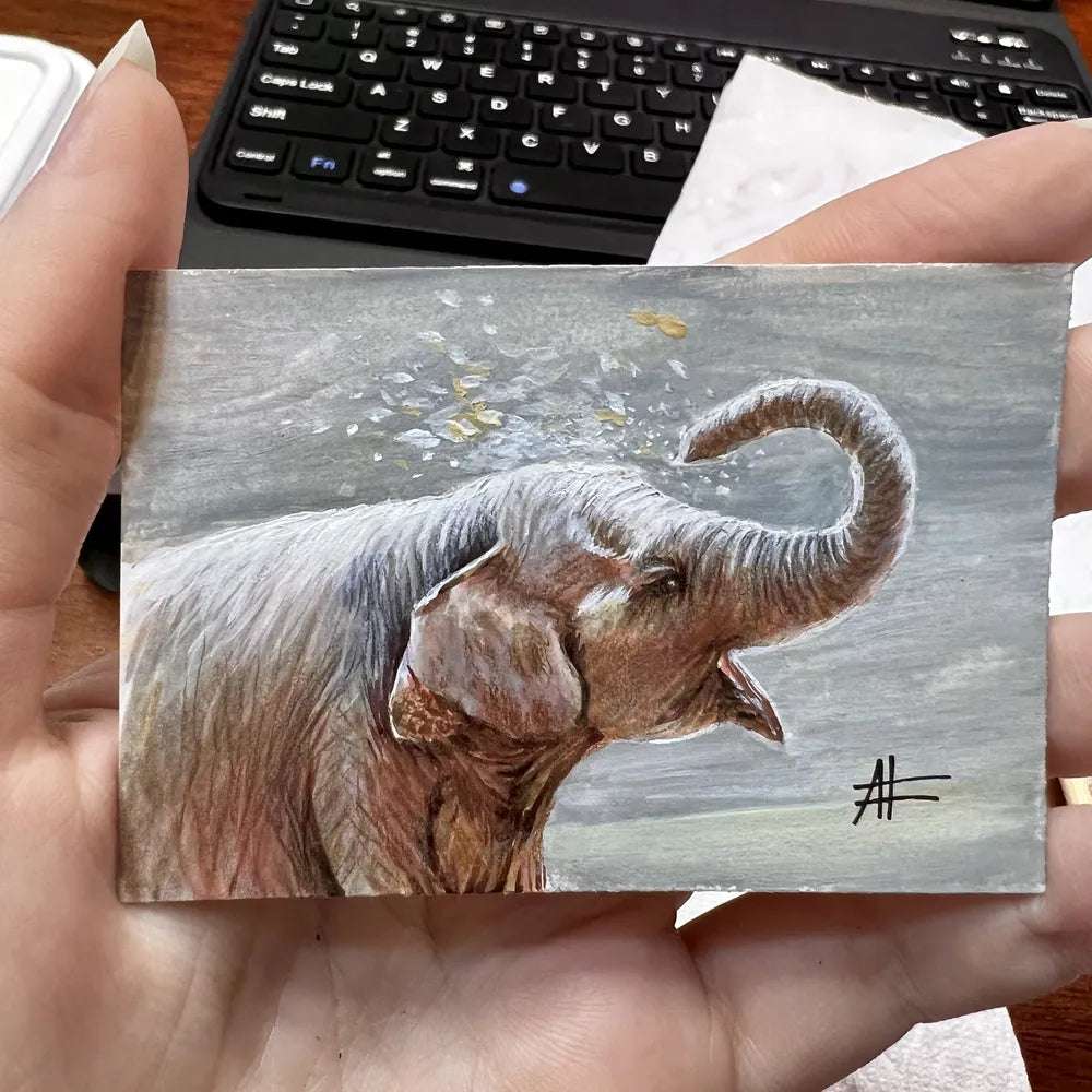 Small card-sized elephant painting held in a hand, illustrating the elephant's detailed features.