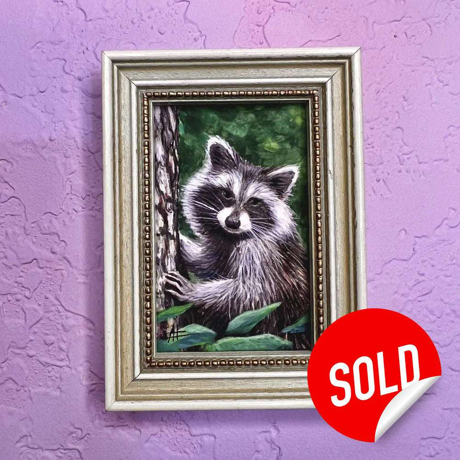 Painting of a raccoon peeking from behind a tree in a golden frame on a purple wall.