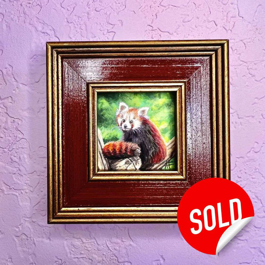 Framed painting of a red panda on a tree limb against a green background on a purple wall.