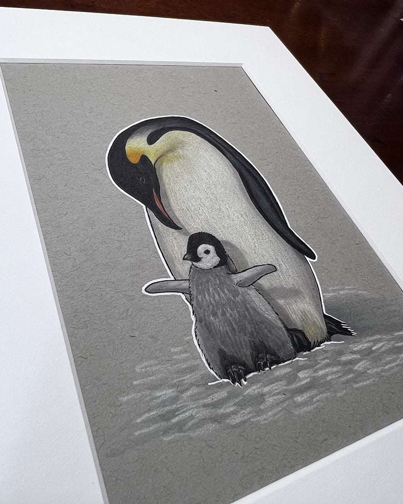 Illustration of a Penguin With Baby - Original Marker Painting on a gray background, displayed on a wooden table.