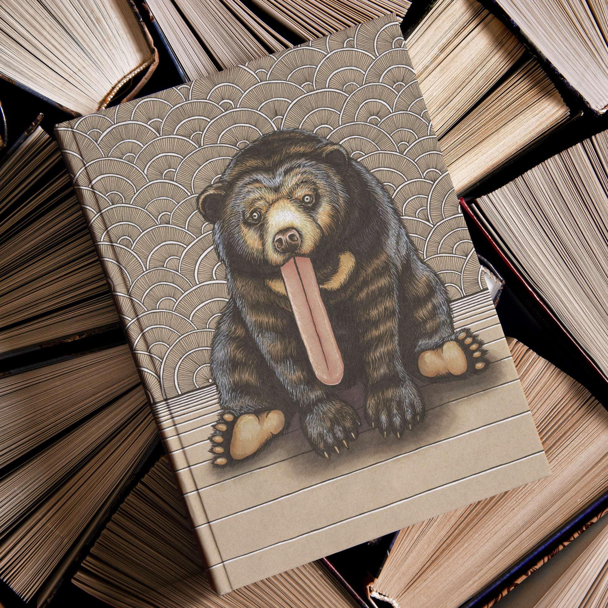 A Sun Bear Journal with an illustrated cover featuring a bear sticking out its tongue, resting on a pile of old books.