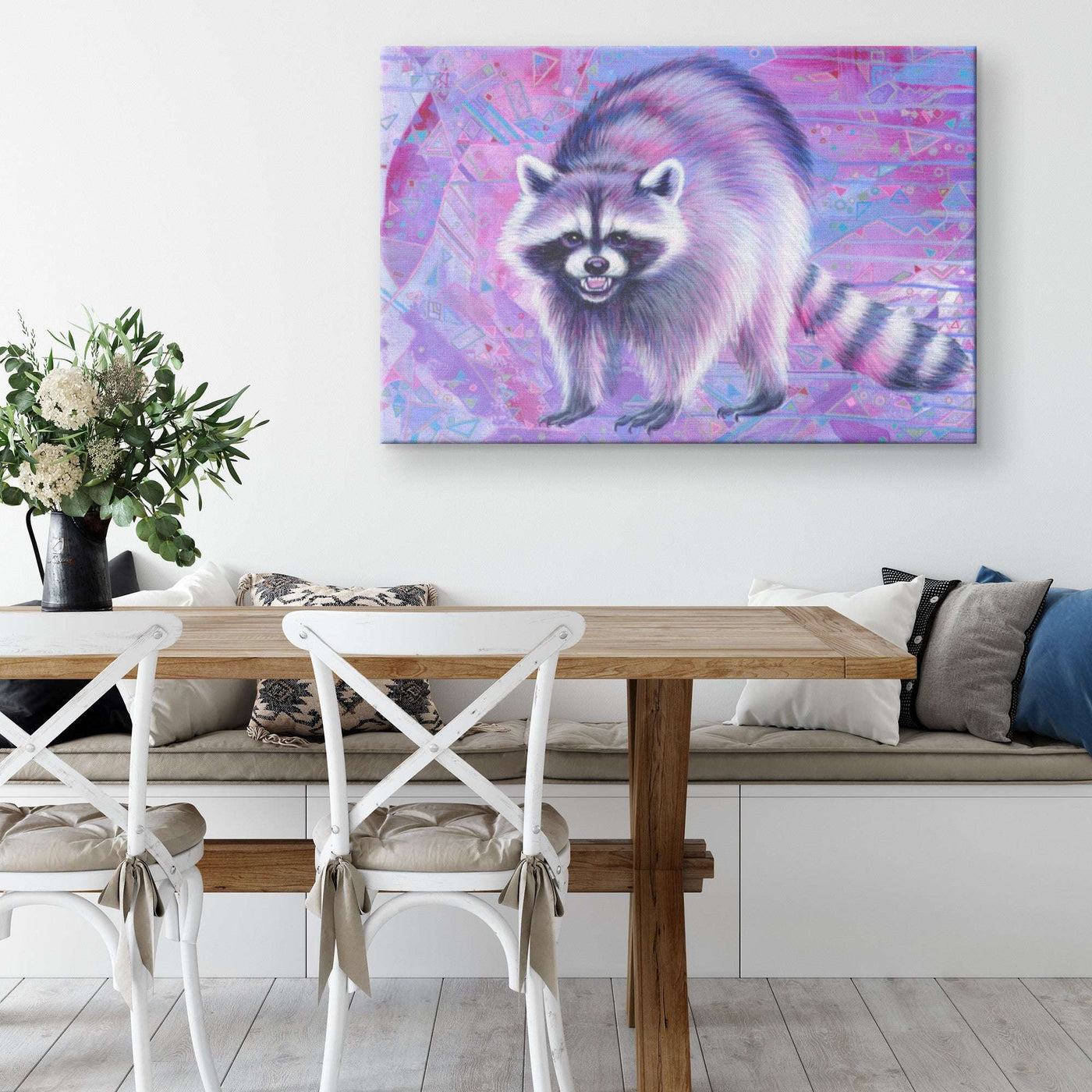 A colorful pink and purple Canvas Raccoon Art Print hanging above a wooden table.