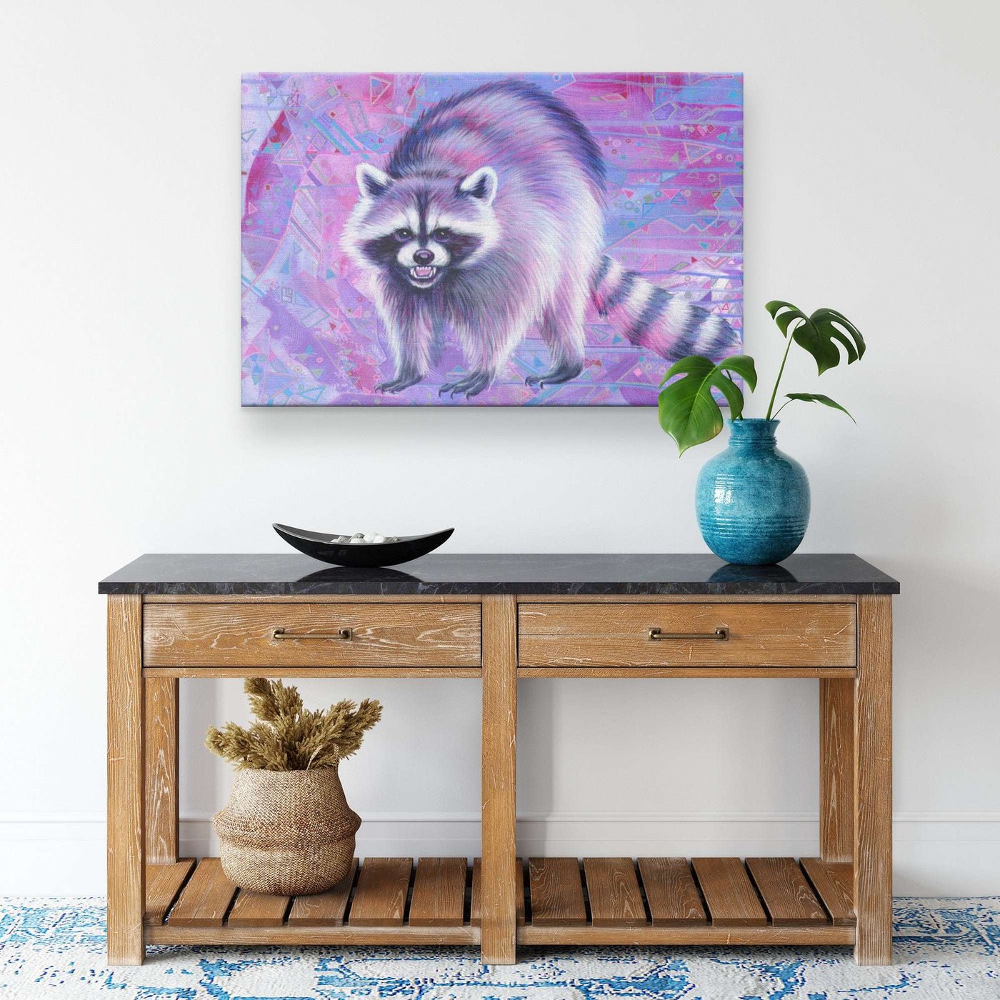 Canvas Raccoon Print of a pink and purple raccoon on a wall above a wooden table.