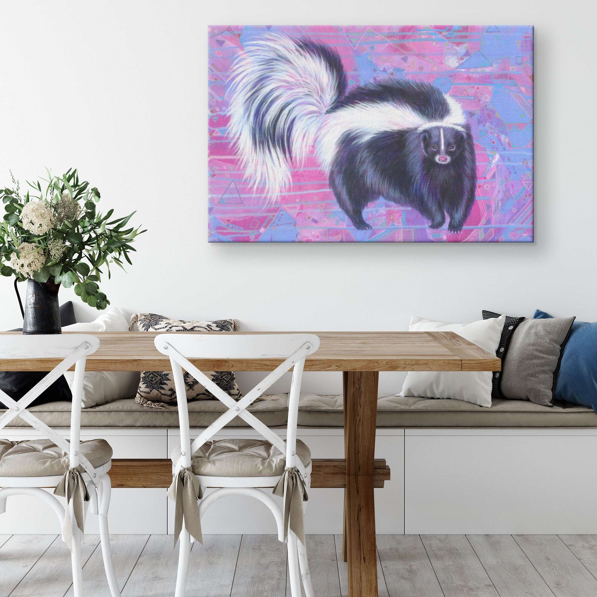 Colorful Canvas Skunk Art Print hanging in a bright living room with white chairs and wooden table.