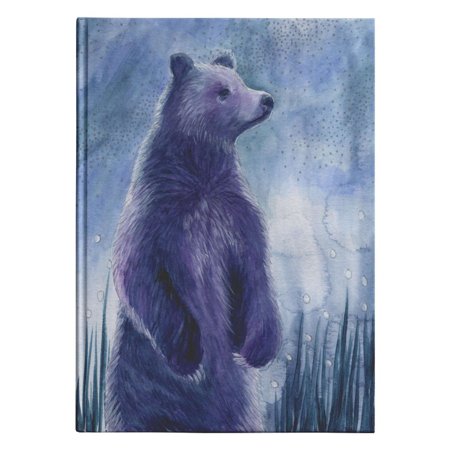 Illustration of a standing bear against a blue, starry night sky and green grass on the cover of the Celestial Bear Journal.
