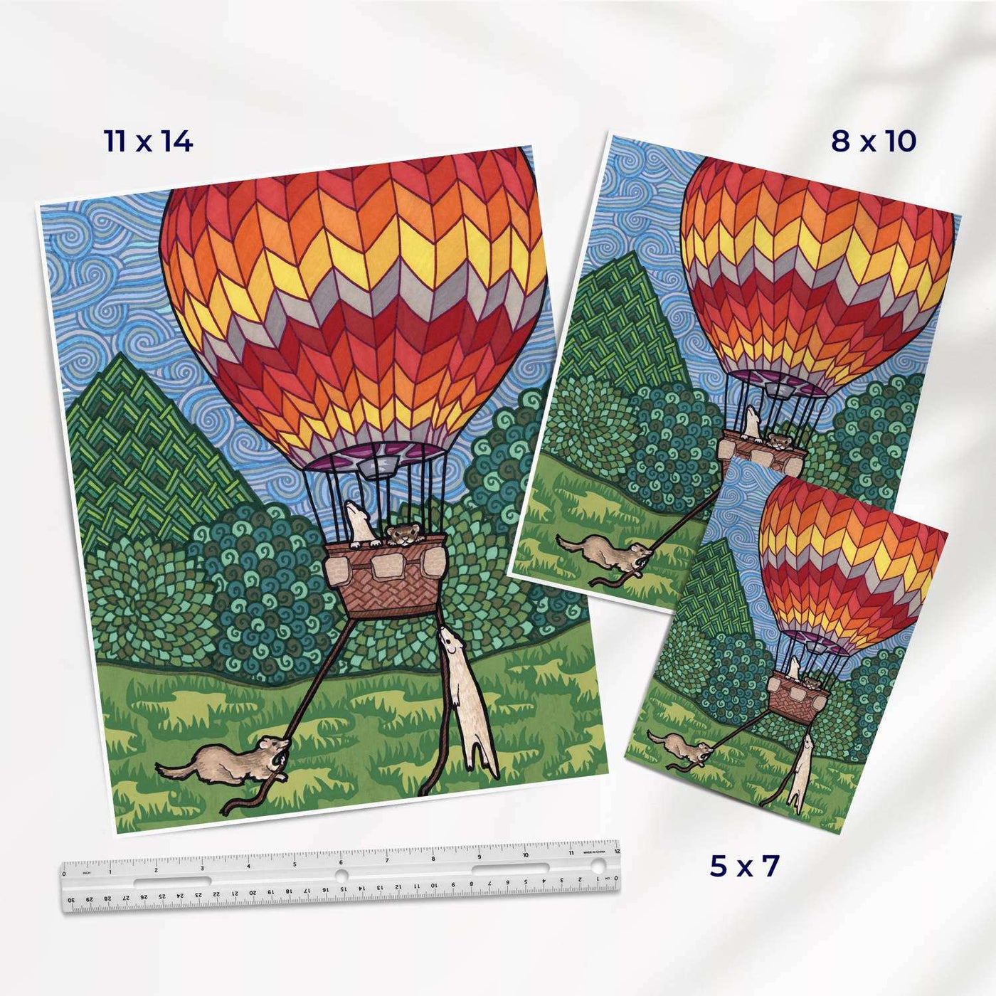 Various art print sizes showing a hot air balloon adventure ferret illustration in various sizes with a ruler for scale.