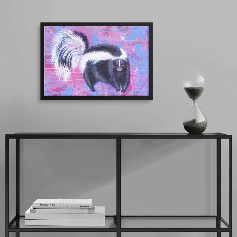 Framed Skunk Art Print of a skunk on a pink and blue background, displayed above a shelf with books and an hourglass, in a modern interior setting.