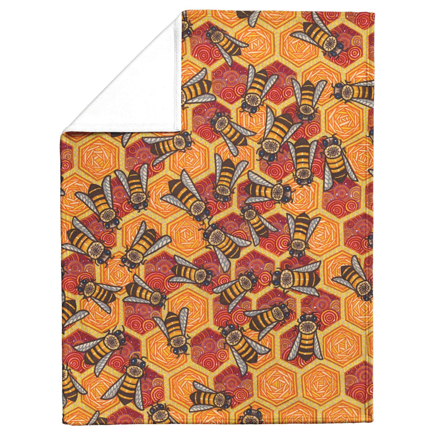 A blanket with a decorative pattern featuring bees and hexagonal shapes in shades of orange and brown, one corner is folded to show the fleece texture