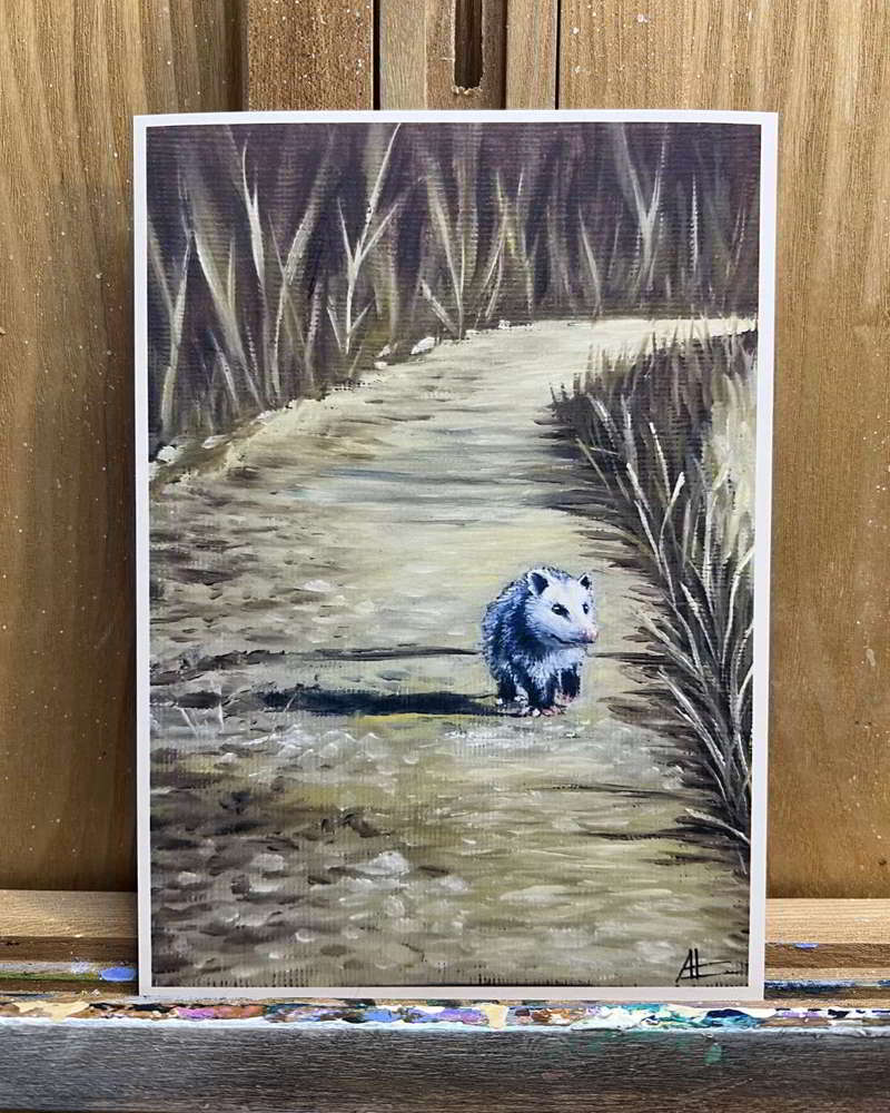 Art print of a woodland path with a lone opossum, resting on an easel.