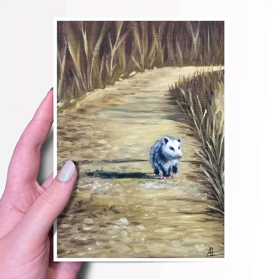 Art print of an opossum walking on a woodland path held by a hand.