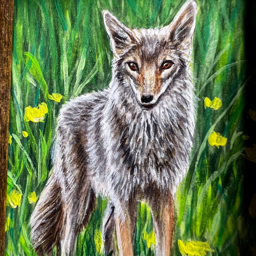 A close-up of a coyote painting with intricate fur detail and yellow flowers.