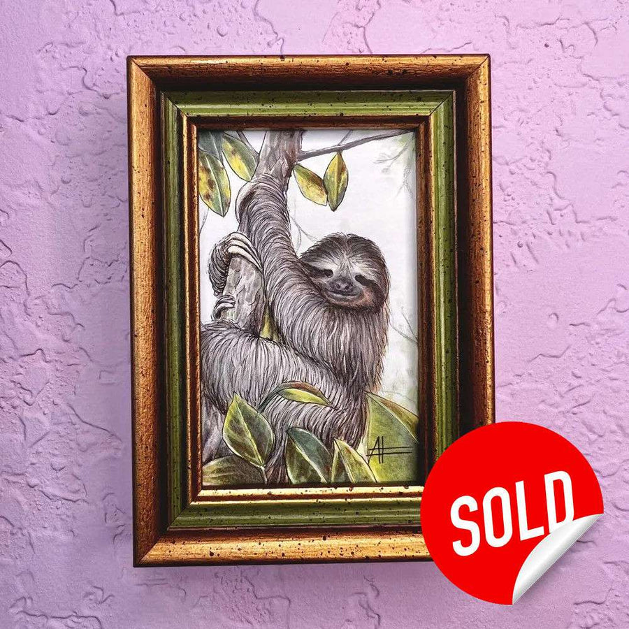 Framed painting of a smiling sloth hanging from a tree, displayed on a purple wall.
