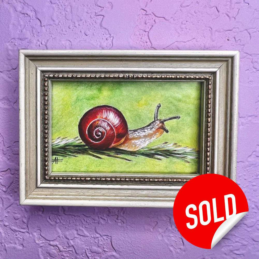 Small painting of a snail with a vibrant red shell on grass, framed and marked sold on a purple wall.