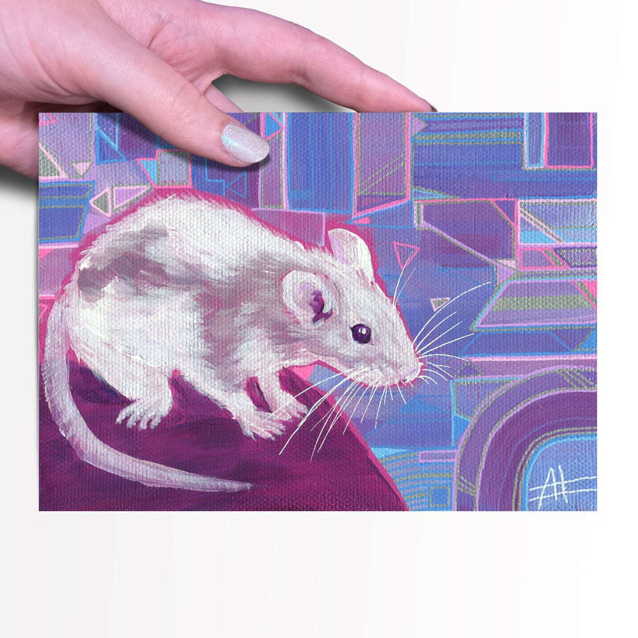 A hand holding a small Ratly Jr. - Fine Art Print, 5x7 depicting a realistic painting of a white mouse on a colorful geometric background.