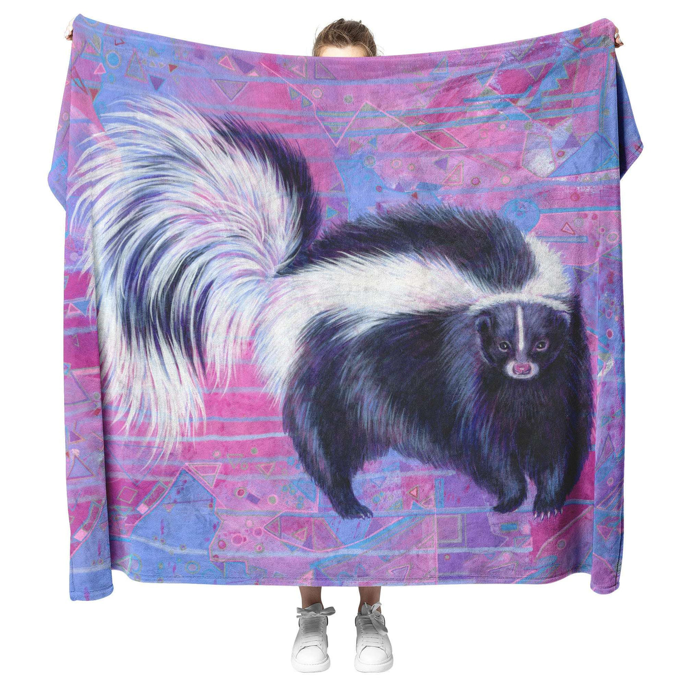 Person holding up a large Skunk Blanket featuring a colorful geometric pattern and a detailed illustration of a skunk.