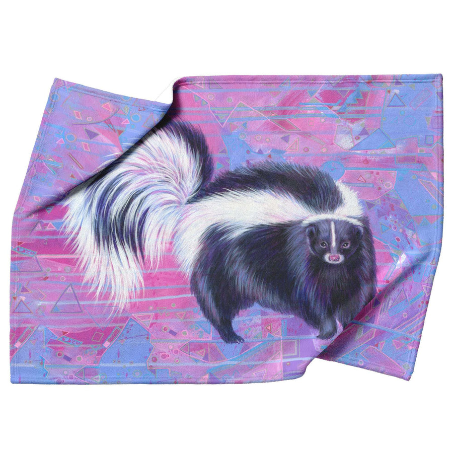A vibrant Skunk Blanket featuring a detailed illustration of a skunk on a geometric patterned background in shades of purple and pink.