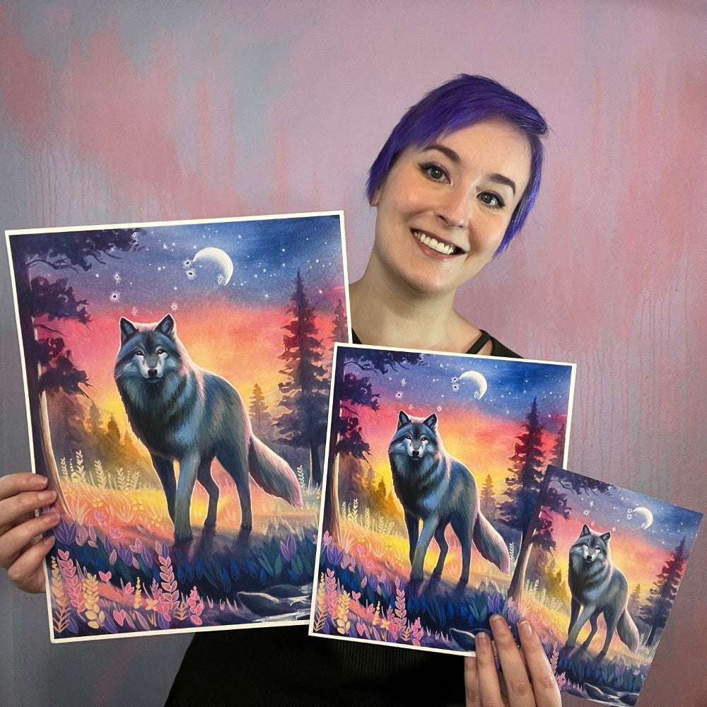 Woman with purple hair smiling and holding three various sizes of art prints featuring "The Wolf (Twilight Watch)" a piece that depicts a mystical wolf in a colorful forest at sunset.